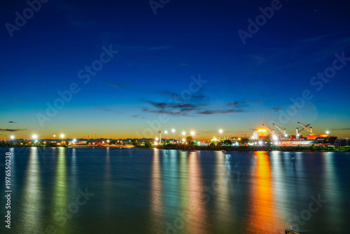 Vibrant industrial harbor lights under a deep blue sky.