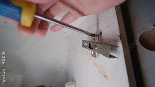 Man Unscrewing Last Screw from Broken Cabinet Hinge Falling Down | Kitchen Furniture Door Hardware Removal Close-Up | Home Repair DIY Process