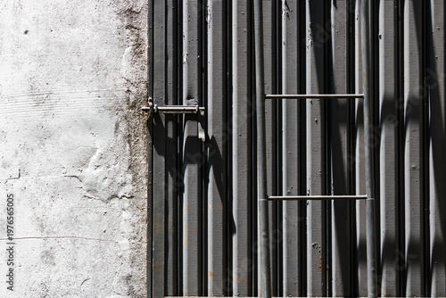 Wallpaper Mural Contrast between a white worn concrete wall and a vertical metal gray gate  with bars.  Torontodigital.ca