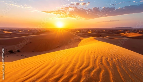 A breathtaking sunset illuminates rolling sand dunes in a vast desert landscape.