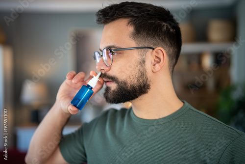 Billede på lærred Man applying nasal spray for nasal congestion relief