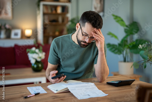 Stressed man calculating home budget and paying bills