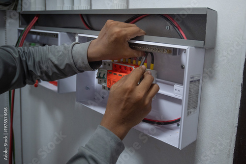 The electrician is connecting the electrical circuits in the control box of the solar power generation system and organizing the wiring in the control cabinet.