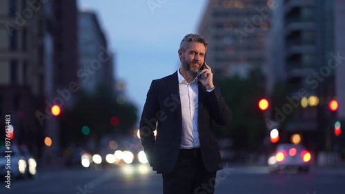 Successful businessman making a call in modern city street. Business man on phone surrounded by bokeh city lights. Entrepreneur talking on smartphone in urban evening scene.