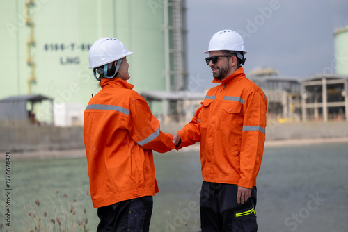 Engineers shaking hands at industrial plant site