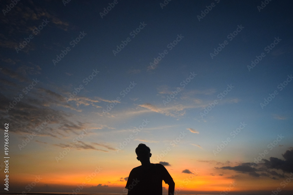 Fototapeta premium Silhouette of a man at the beach with sunset as a background