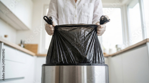 Wallpaper Mural Hands in protective gloves placing a black trash bag into a stainless steel garbage can in a modern kitchen Torontodigital.ca