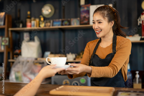 Smiling barista serving coffee to customer in cafe