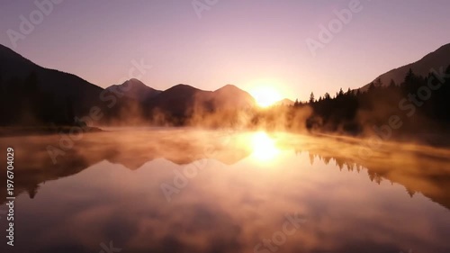 Golden light on foggy lake in mountains at sunrise