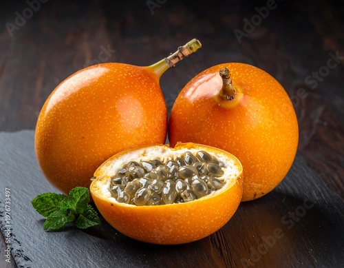 Close-up of granadilla fruits, sliced one, with mint on a dark surface