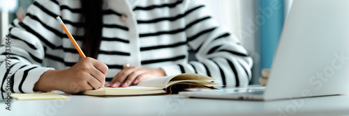 Female Asian student using laptop for online learning at home