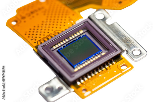 A modular circuit board containing a digital processor and photocell components of a digital camera, on a white background. It is a hardware technology device for repairing digital cameras.