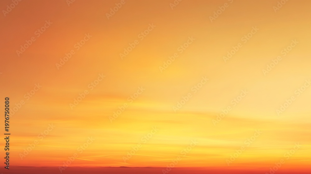 Fototapeta premium A vibrant orange and yellow sunset sky with warm hues and soft clouds