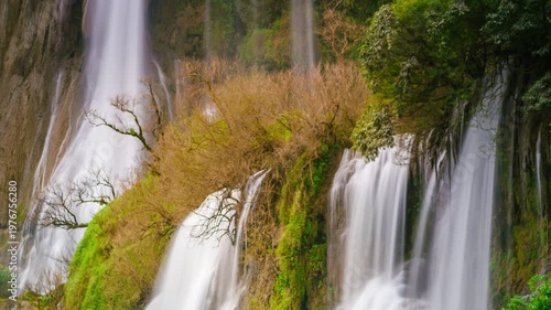 Breathtaking long exposure of Thi Lo Su Waterfall in Thailand, featuring silky white water cascading over lush green cliffs and autumn foliage. Perfect for nature, travel, and tranquility themes.