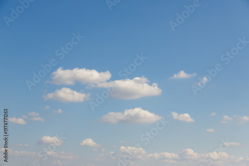 Many small white cumulus clouds scattered across a vast and clear blue sky