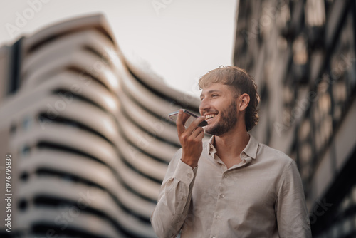 Young entrepreneur recording a voice note on his phone in the city center