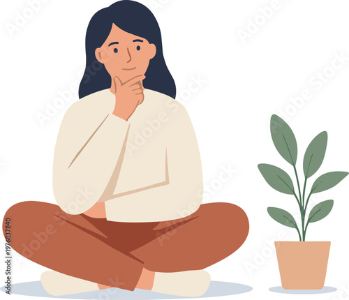 Woman sits cross-legged next to plant with thoughtful expression indoors
