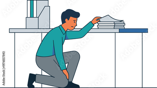 Man in office kneeling beside desk reaching for stack of papers
