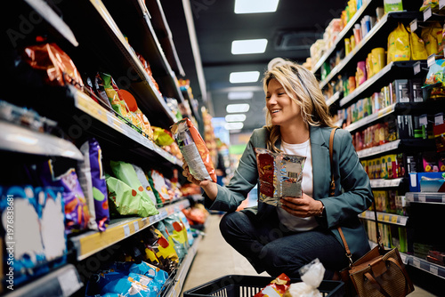 Tableau sur toile Happy woman buying snacks in supermarket.