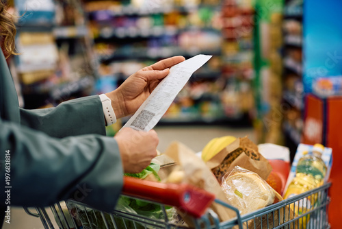 Close up of woman checking the bill after buying groceries in supermarket.