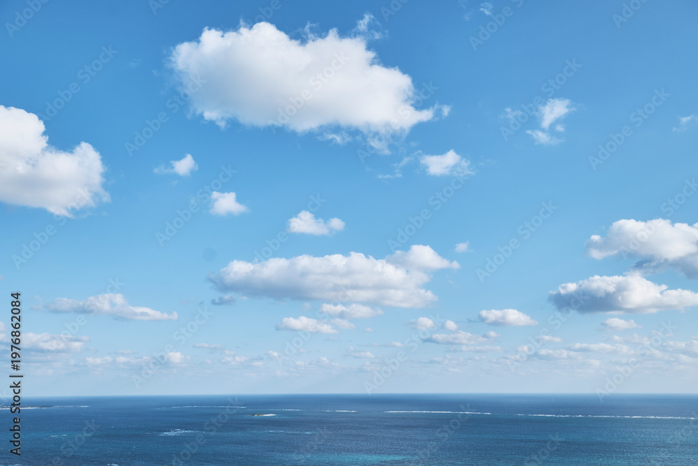 Obraz premium Open sea horizon beneath bright blue sky with scattered clouds