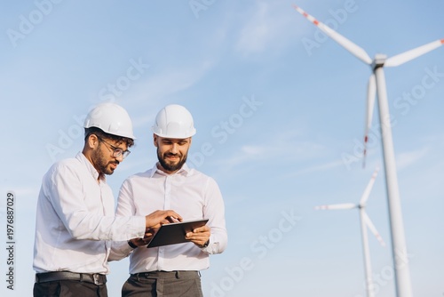 Engineers using tablet working in wind turbine power plant