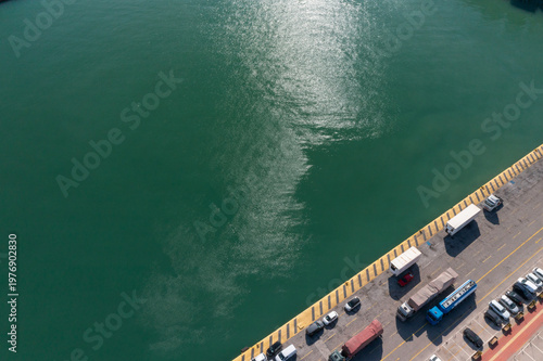 Top-down view of Piraeus port pier and turquoise water with parked vehicles in Athens, Greece