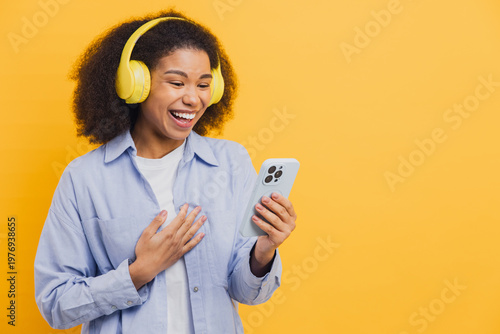 African American woman laughing wearing headphones enjoying smartphone content