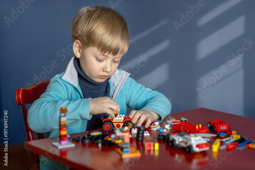 Vászonkép Six year old boy playing with assembled construction toys at a table