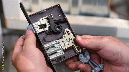 Person hands holding an open door lock mechanism with keys to show its internal structure and components.