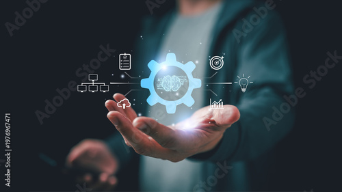 Man presenting glowing AI gear icon with connected digital symbols, representing automation, machine learning, workflow optimization, and smart technology integration in modern business environment.