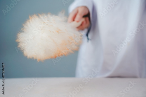 фотографія Close-up of a medical professional in a white coat holding a fluffy feather duster