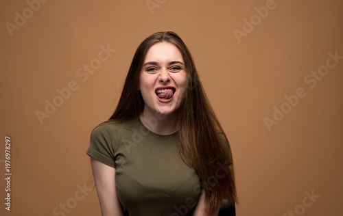 Young woman making a playful grimace while sticking out tongue, expressing a humorous and goofy mood