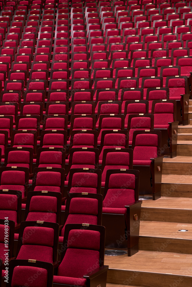 Fototapeta premium Pattern of red theater chairs and aisle steps in close up