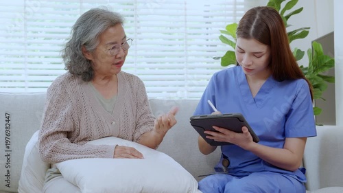 Asian woman nurse examining senior patient arm for physical therapy and record note on tablet, caregiver or doctor checking hand pain of elderly woman, medical rehabilitation.