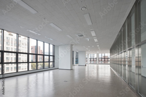 Long bright corridor with glass wall in modern office building