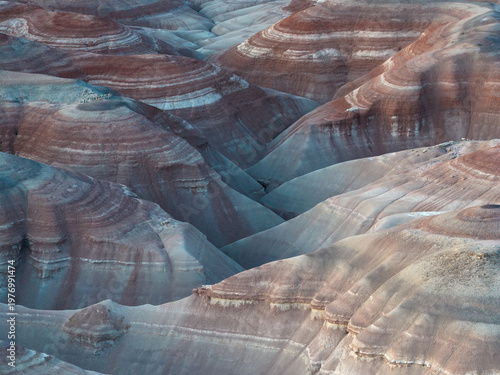 Aerial view of layered earth tones create a painterly landscape, where shadows accentuate the undulating terrain., Hanksville, Utah, United States.