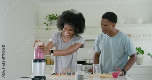 African American couple placing blender cup chopping fruit making pink smoothie for two in kitchen