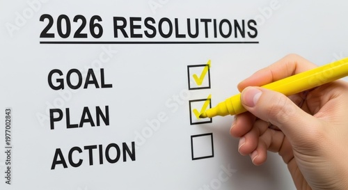 A hand holding a yellow pen checking boxes for 2026 resolutions