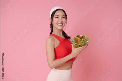 Healthy eating lifestyle concept with Asian woman holding fresh salad bowl smiling after workout nutrition balance diet control wellness routine and fitness motivation