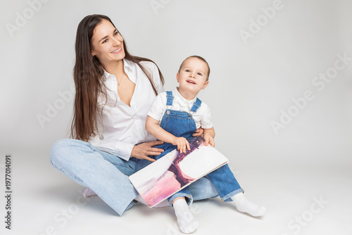 One Smiling Cheerful Happy Couple Woman And Child Boy In Casual Clothing Having Mommy Little Kid Son Hug Cuddle Reading Book Together on White.