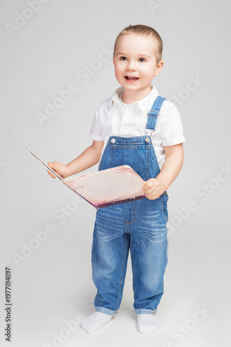 Portrait of Male Kid Boy Of 2-3 Years Old Wearing Jeans Jacket White Shirt Holding Book Isolated on White Background As Children Portrait To Convey Childhood  Concept.
