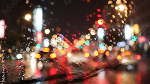 Rainy Night Cityscape through a Car Windshield with Bokeh Lights, Urban Evening Drive, and Traffic Reflections