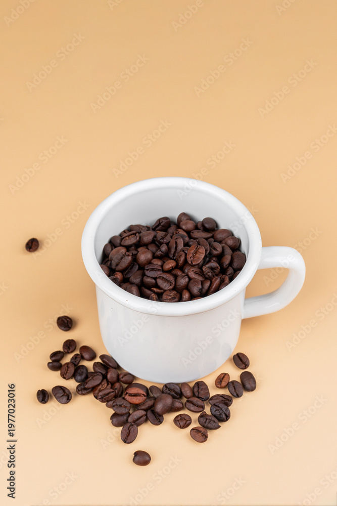 Obraz premium A white coffee cup with coffee beans, against on cream background.