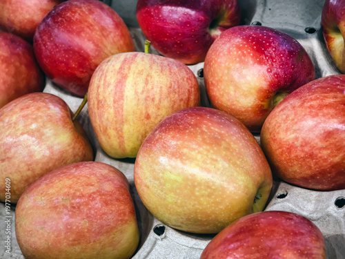 Red apples are stacked together in a tray at a local market during the afternoon hours in fall