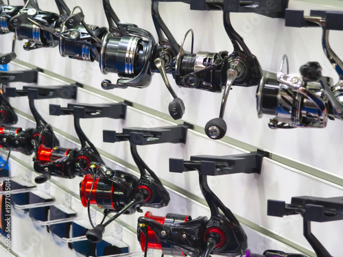 Different types of fishing reels displayed on a wall at a sporting goods store in bright lighting for customers to look at