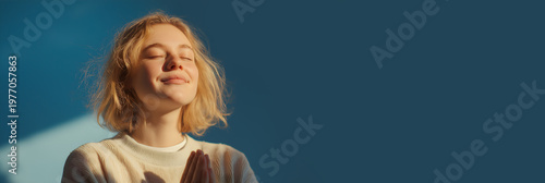 Banner of a young woman feeling grateful and thankful isolated on a blue background. Inspirational life concept. Copy space.