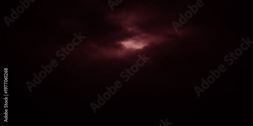 A dark blue night sky with abstract storm clouds and a radiant sun creates a dramatic nature cloudscape of light and atmosphere