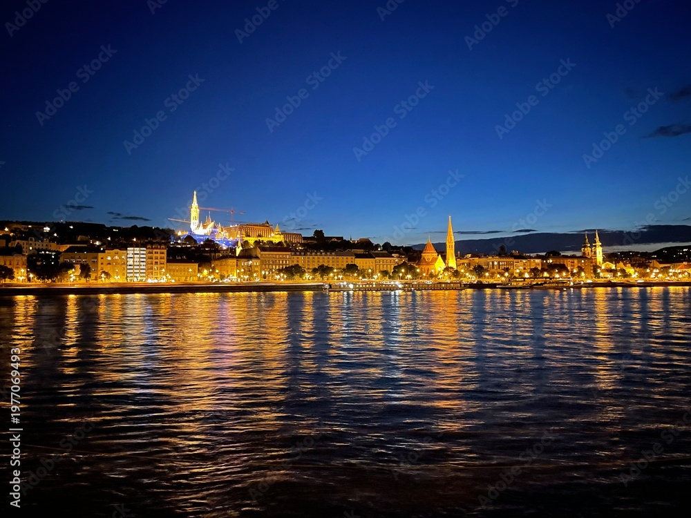 Fototapeta premium Illuminated waterfront city skyline reflected in water at blue hour