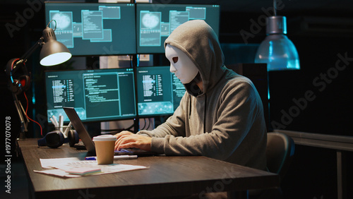 Foto Cyber scammer wearing mask and hood to hack computer system, breaking into servers to steal big data